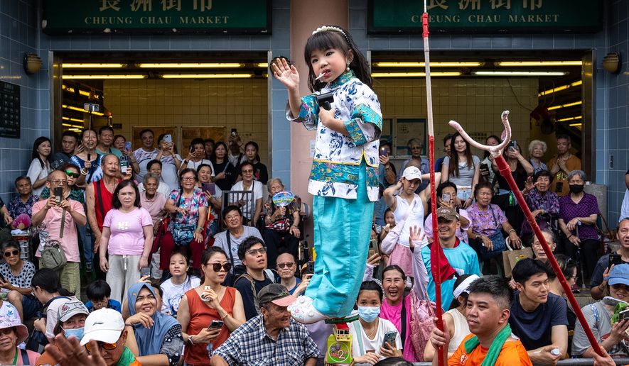 A child is hoisted up as participants take part in the Piu Sik Parade at the Bun Festival in Cheung Chau Island in Hong Kong, Sunday, May 24, 2026. (AP Photo/Chan Long Hei)