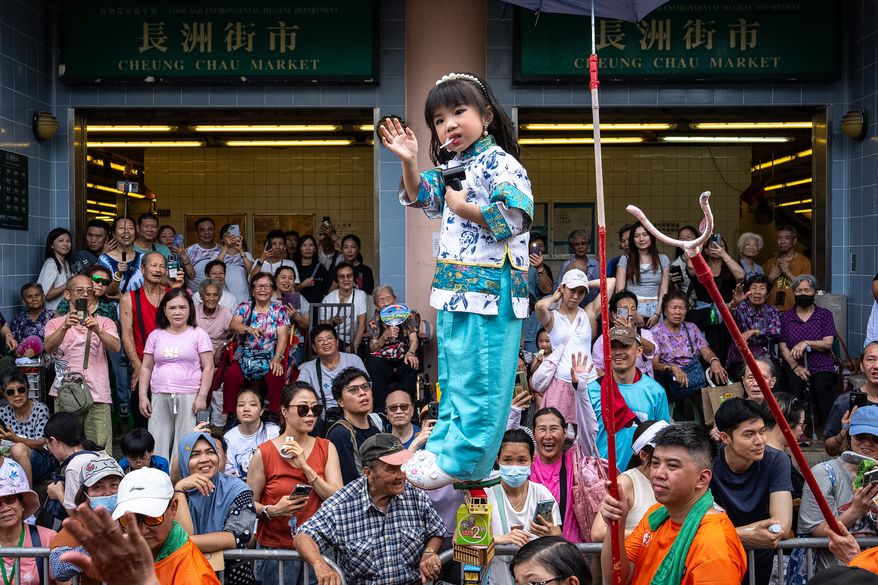 A child is hoisted up as participants take part in the Piu Sik Parade at the Bun Festival in Cheung Chau Island in Hong Kong, Sunday, May 24, 2026. (AP Photo/Chan Long Hei)