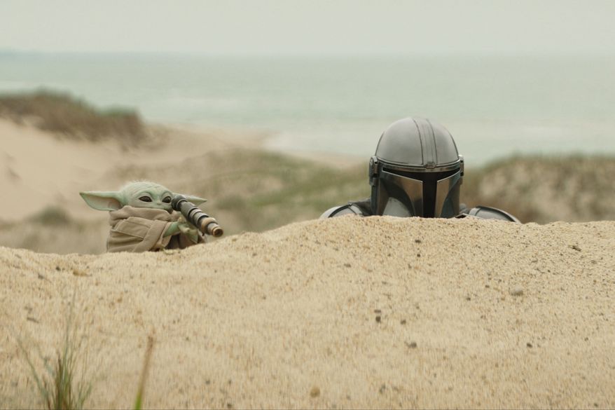 This image released by Disney shows The Mandalorian, portrayed by Pedro Pascal, right, and Grogu in a scene from Lucasfilm's "Star Wars: The Mandalorian and Grogu." (Lucasfilm Ltd. - Disney via AP)