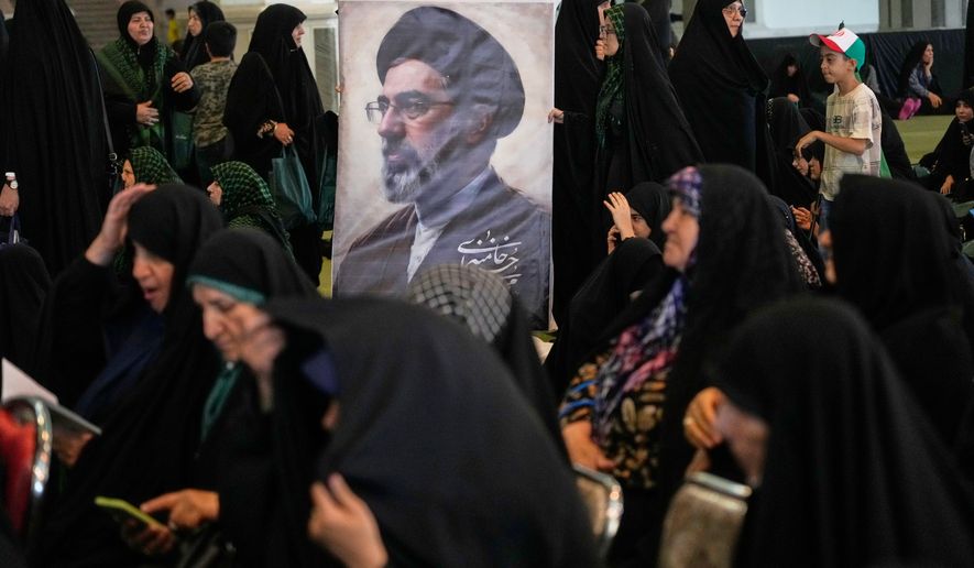 Women gather around a portrait of Iran's Supreme Leader, Ayatollah Mojtaba Khamenei, during a ceremony honoring the armed forces and those killed in the war with Israel and the U.S. at the Imam Khomeini Grand Mosque in Tehran, Iran, Sunday, May 24, 2026. (AP Photo/Vahid Salemi)