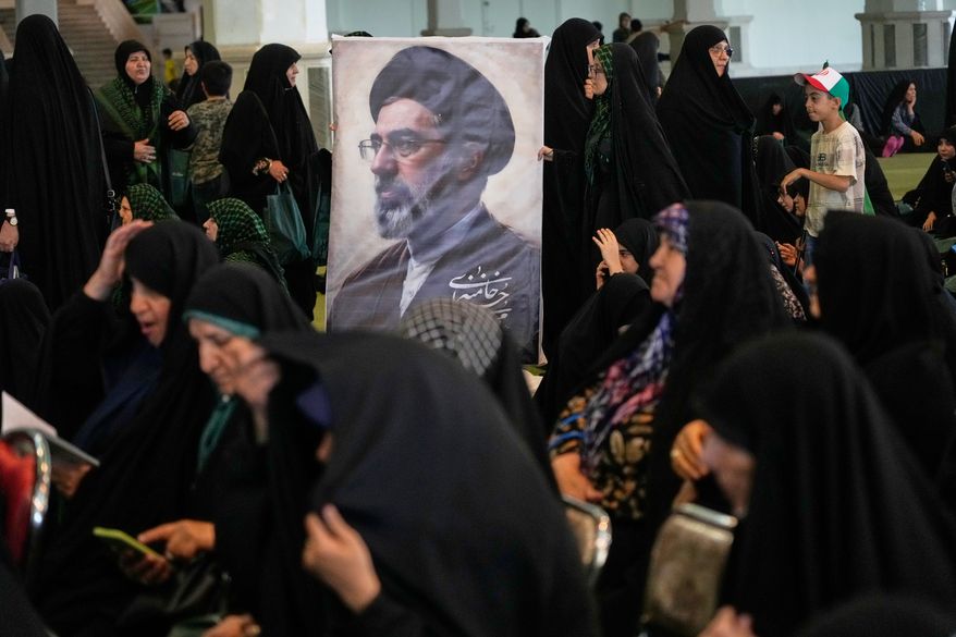 Women gather around a portrait of Iran's Supreme Leader, Ayatollah Mojtaba Khamenei, during a ceremony honoring the armed forces and those killed in the war with Israel and the U.S. at the Imam Khomeini Grand Mosque in Tehran, Iran, Sunday, May 24, 2026. (AP Photo/Vahid Salemi)