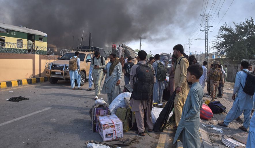 Volunteers look for victims from an overturned train coach on a railway track as survivors wait for transport at the site of bomb explosion, in Quetta, Pakistan, Sunday, May 24, 2026. (AP Photo/Arshad Butt)