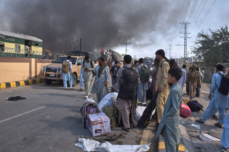 Volunteers look for victims from an overturned train coach on a railway track as survivors wait for transport at the site of bomb explosion, in Quetta, Pakistan, Sunday, May 24, 2026. (AP Photo/Arshad Butt)