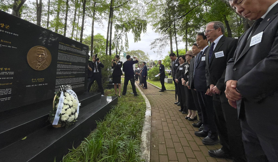 VIPs bow in front of the memorial to legendary U.S. operative and soldier, Gen. John Singlaub, who famously opposed President Jimmy Carter's initiative to withdraw U.S. troops from South Korea, at Imjingak, just south of the DMZ. (Andrew Salmon/The Washington Times)