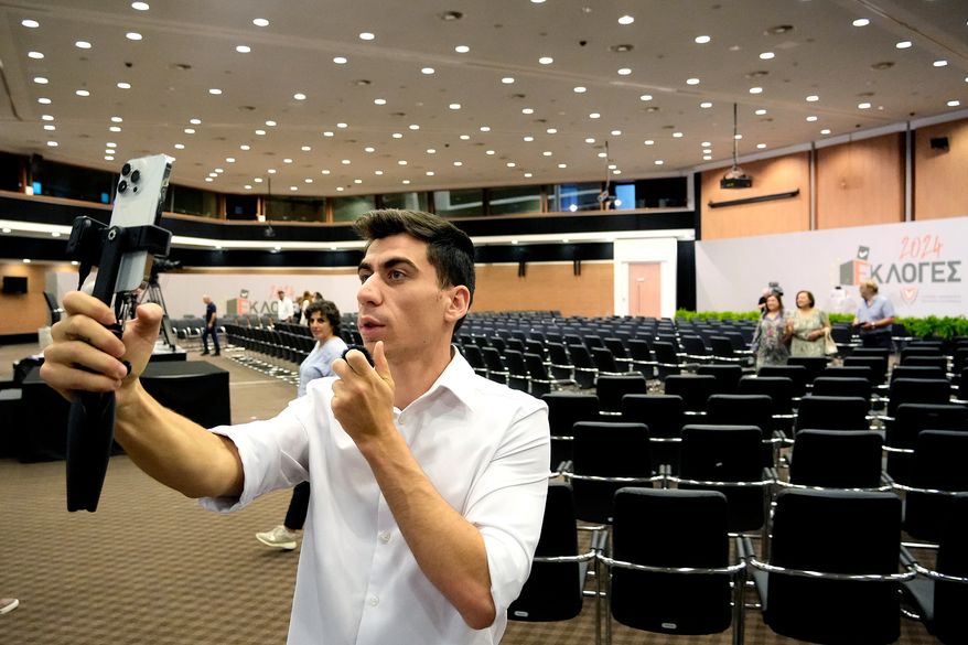 FILE - Popular YouTuber and TikToker with millions of online followers Fidias Panayiotou holds his cell phone after his proclamation as the winner of one of six seats allotted to Cyprus in the European Parliament in Nicosia, Cyprus, Tuesday, June 11, 2024. (AP Photo/Petros Karadjias, File)