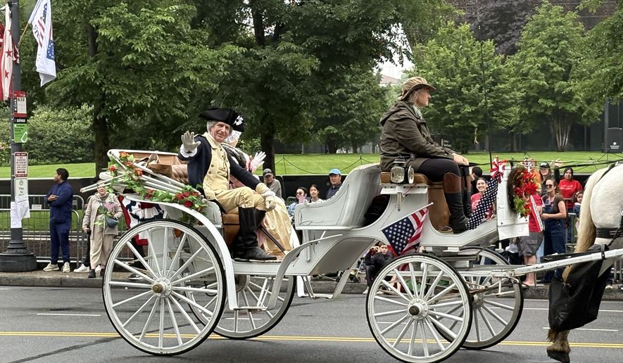 A George Washington impersonator waves to people along Constitution Avenue NW as his carriage rides past the National Museum of African American History and Culture (Matt Delaney/The Washington Times)