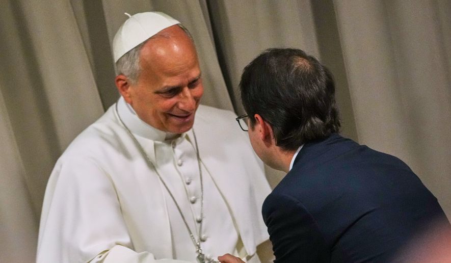 Pope Leo XIV, left, greets Anthropic co-founder Christopher Olah during the presentation of the Pope's first encyclical, "Magnifica humanitas: On Safeguarding the Human Person in the Time of Artificial Intelligence," at the Vatican, Monday, May 25, 2026. (AP Photo/Alessandra Tarantino)