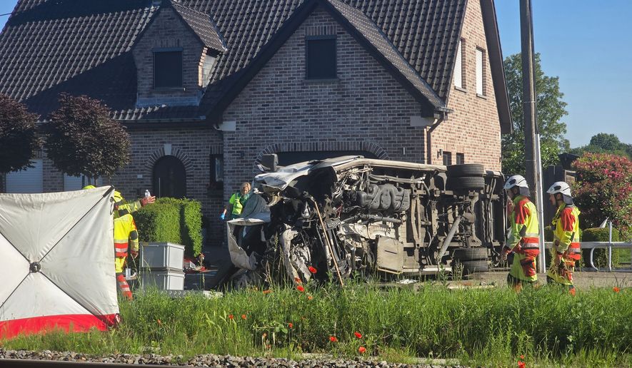 Rescue workers on the scene of a crash between a train and vehicle in Buggenhout, Belgium, Tuesday, May 26, 2026. (AP Photo/Koen Baten)
