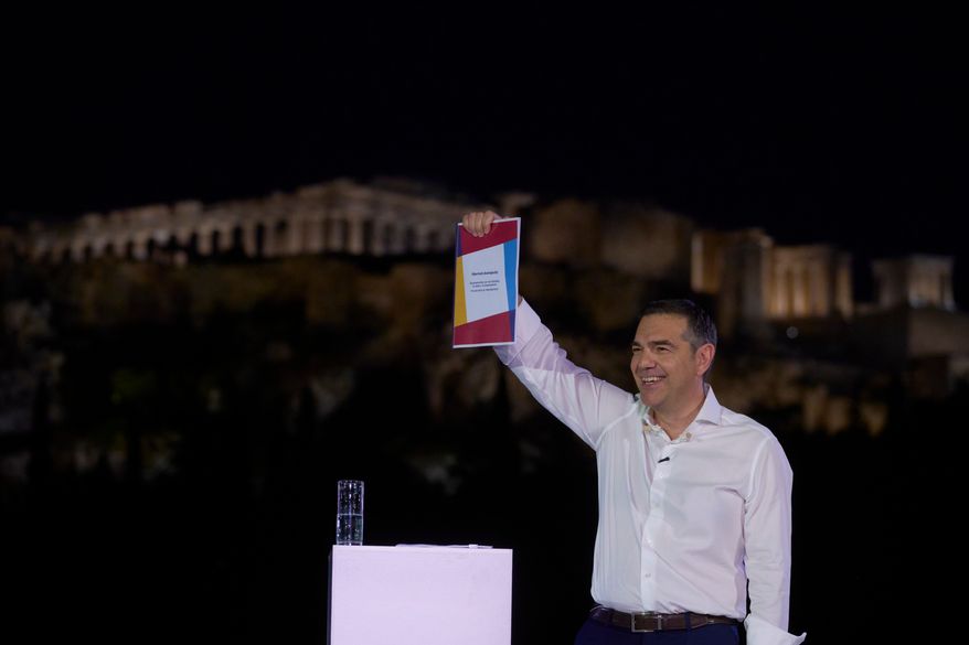Former left-wing Prime Minister Alexis Tsipras holds the founding manifesto of his new political party as speaks to supporters in front of the ancient Acropolis , ahead of elections next year, in Athens, on Tuesday, May 26, 2026. (AP Photo/Petros Giannakouris)