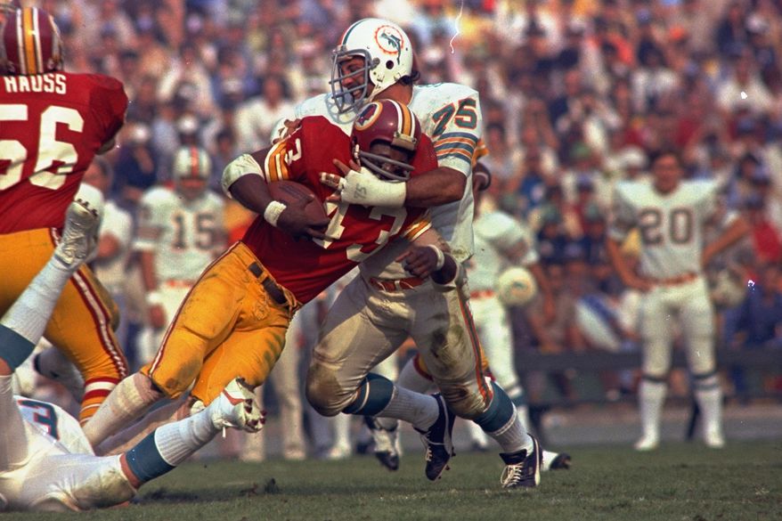 Washington Redskins running back Larry Brown (43) is stopped in his tracks by Miami Dolphins defender Manny Fernandez (75) during the NFL football Super Bowl VII game in Los Angeles, Jan. 14, 1973. (AP Photo/File)