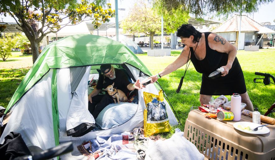 Jan De Jonge and fiancé Sher Stuckman set up a tent with their belonging and pet outside the Elks Lodge in Garden Grove, Calif., on Monday, May 25, 2026. (AP Photo/Ethan Swope)