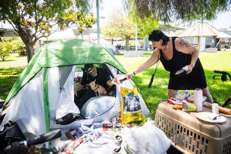Jan De Jonge and fiancé Sher Stuckman set up a tent with their belonging and pet outside the Elks Lodge in Garden Grove, Calif., on Monday, May 25, 2026. (AP Photo/Ethan Swope)