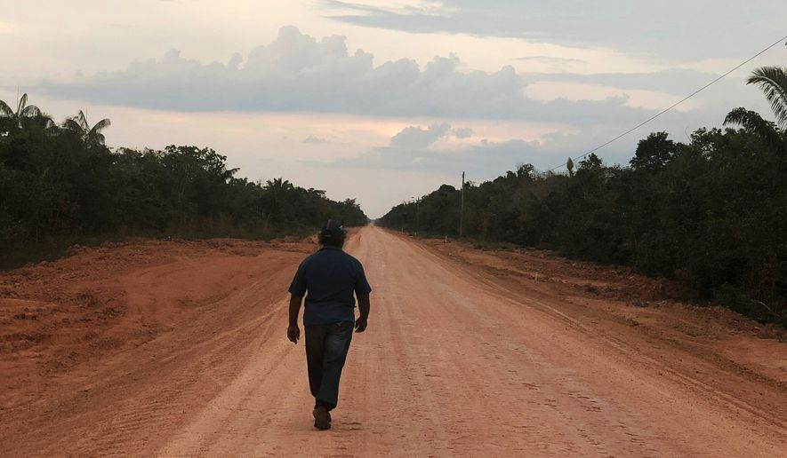 A man walks down an unpaved stretch of highway BR-319 in the Brazilian Amazon between the cities of Manaus and Porto Velho on Aug. 10, 2018. (AP Photo/Fabiano Maisonnave, File)