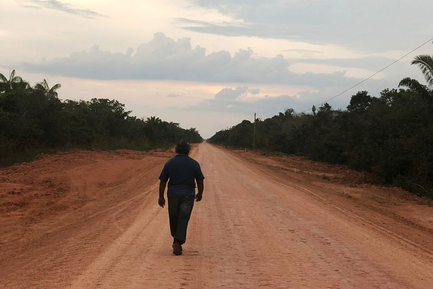 A man walks down an unpaved stretch of highway BR-319 in the Brazilian Amazon between the cities of Manaus and Porto Velho on Aug. 10, 2018. (AP Photo/Fabiano Maisonnave, File)