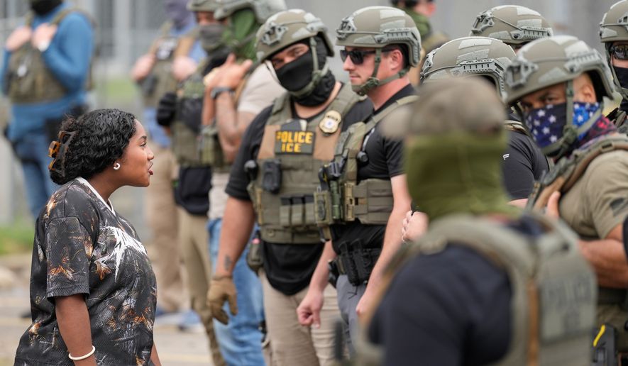 A protester talks to masked federal agents standing outside the Delaney Hall detention center during a protest against the transfer of detainees on Wednesday, May 27, 2026, in Newark, N.J. (AP Photo/Seth Wenig)