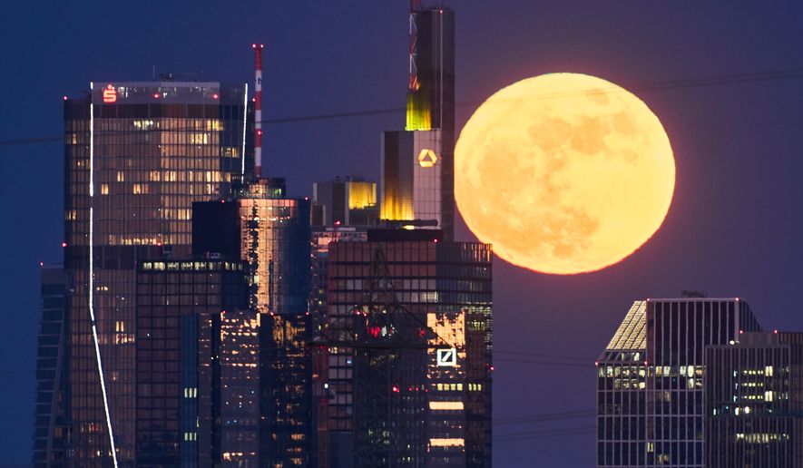 The full moon rises behind the buildings of the banking district in Frankfurt, Germany, Friday, May 1, 2026. (AP Photo/Michael Probst) ** FILE **