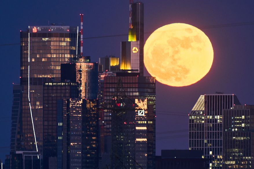The full moon rises behind the buildings of the banking district in Frankfurt, Germany, Friday, May 1, 2026. (AP Photo/Michael Probst) ** FILE **