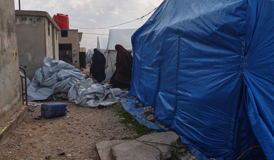 FILE - Unidentified women walk between tents in a section of the camp housing Australian family members of suspected Islamic State militants in the Roj Camp in eastern Syria, Feb. 18, 2026. (AP Photo/Baderkhan Ahmad, File)