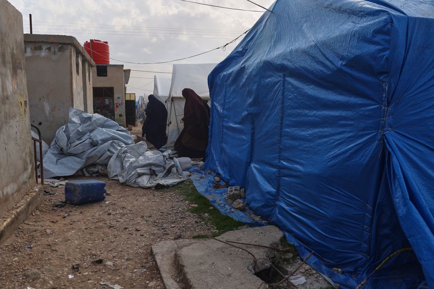 FILE - Unidentified women walk between tents in a section of the camp housing Australian family members of suspected Islamic State militants in the Roj Camp in eastern Syria, Feb. 18, 2026. (AP Photo/Baderkhan Ahmad, File)