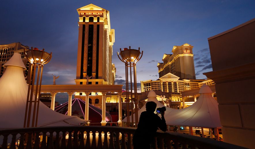 FILE - A man takes pictures of Caesars Palace hotel and casino in Las Vegas, Jan. 12, 2015. (AP Photo/John Locher, File)