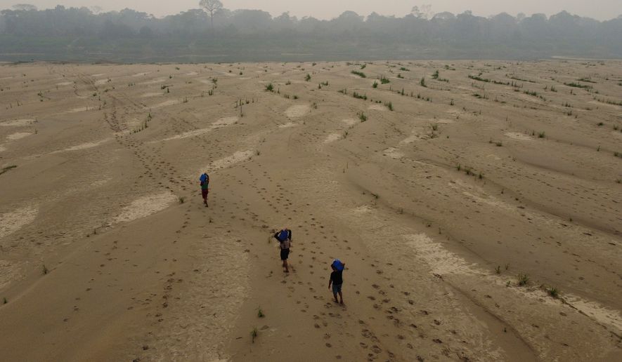 FILE - Residents transport drinking water from Humaita to the Paraizinho community, along the dry Madeira River, a tributary of the Amazon River, during the dry season, Amazonas state, Brazil, Sept. 8, 2024. (AP Photo/Edmar Barros, File)