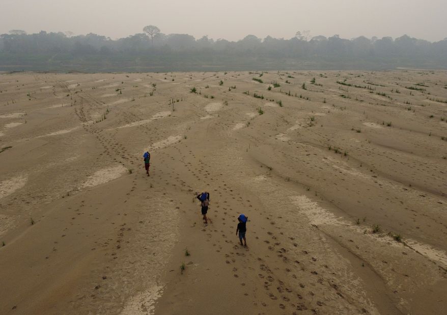 FILE - Residents transport drinking water from Humaita to the Paraizinho community, along the dry Madeira River, a tributary of the Amazon River, during the dry season, Amazonas state, Brazil, Sept. 8, 2024. (AP Photo/Edmar Barros, File)