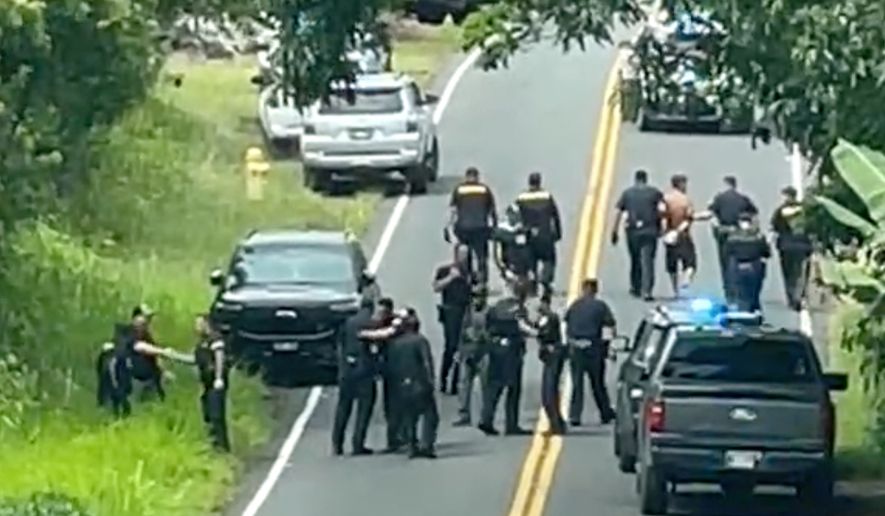 Police arrest a man accused of multiple killings, right, on Thursday, May 28, 2026, in Kaimu, Hawaii. (Deborah Davis via AP)