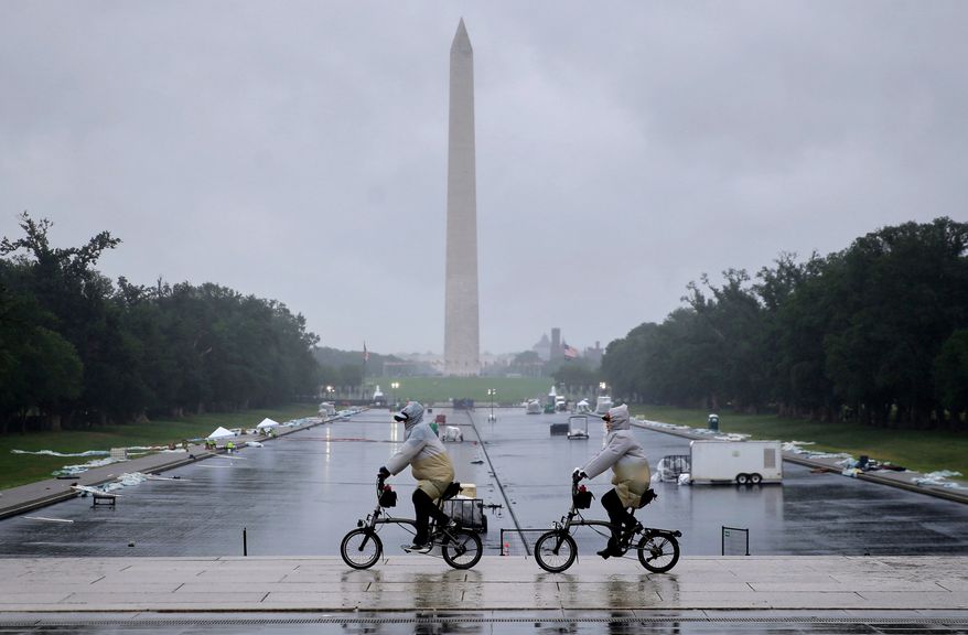 Tourists ride bicycles near the Lincoln Memorial, as a blue protective coating as part of a renovation project to the Lincoln Memorial Reflecting Pool, is seen in the background, Friday, May 22, 2026, in Washington. The Washington Monument stands in he background. (AP Photo/Rahmat Gul)