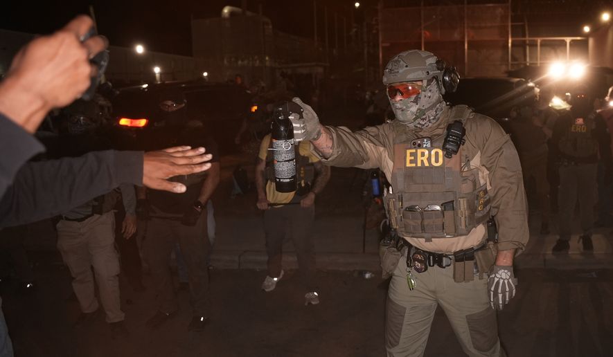 A federal immigration officer aims an OC canister at protesters outside Delaney Hall detention center Thursday, May 28, 2026, in Newark, N.J. (AP Photo/Angelina Katsanis)