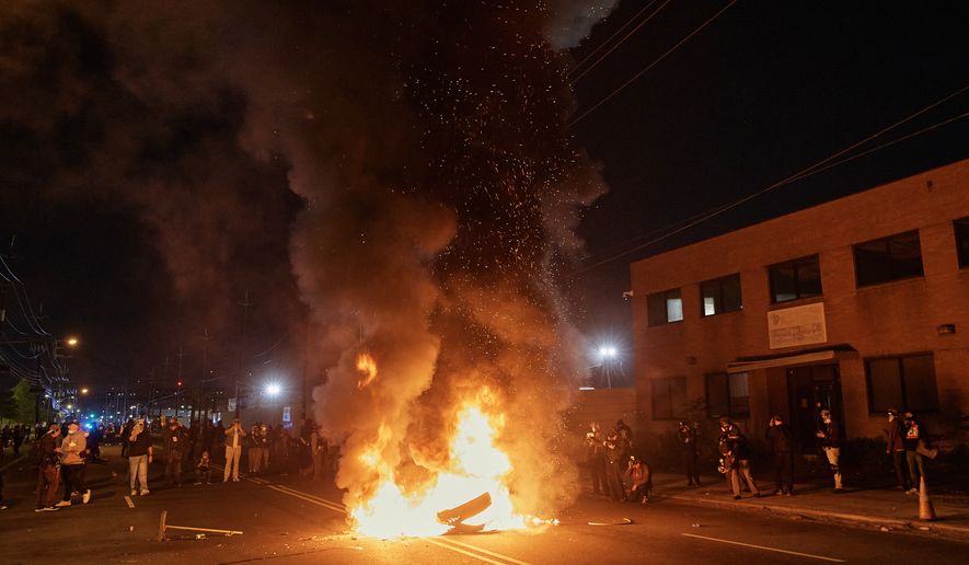People watch a burning barricade near the Delaney Hall detention center during a protest against the transfer of detainees and federal immigration policies on Saturday, May 30, 2026, in Newark, N.J. (AP Photo/Andres Kudacki)