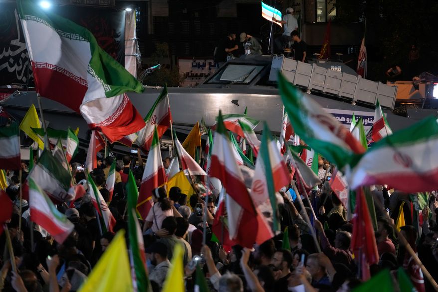 An assault speed boat is displayed by Iran's Revolutionary Guard as demonstrators wave Iranian flags in a pro-government gathering at Islamic Revolution Square in Tehran, Iran, Saturday, May 30, 2026. (AP Photo/Vahid Salemi)