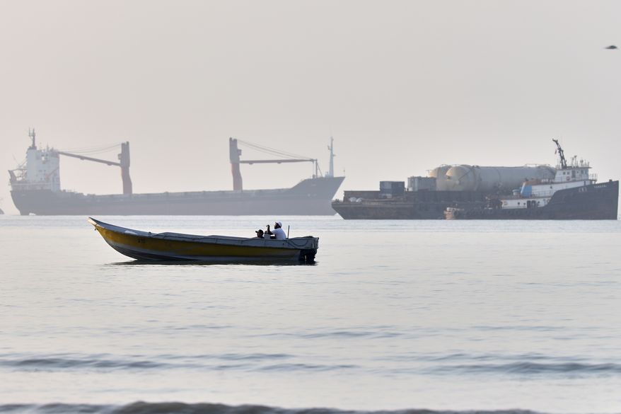 A small boat moves along the shoreline where an a cargo vessel, tugboat and industrial barge are all anchored in the Strait of Hormuz off Bandar Abbas, Iran, Monday, June 1, 2026. (Amirhosein Khorgooi/ISNA via AP)