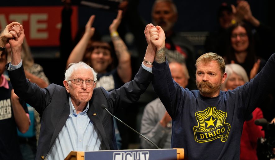 Graham Platner, Democratic candidate for U.S. Senate, and Sen. Bernie Sanders, left, join hands at an event in Orono, Maine, Sunday, May 24, 2026. (AP Photo/Robert F. Bukaty)