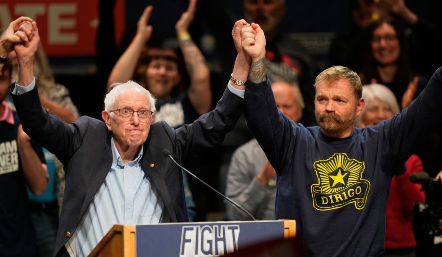Graham Platner, Democratic candidate for U.S. Senate, and Sen. Bernie Sanders, left, join hands at an event in Orono, Maine, Sunday, May 24, 2026. (AP Photo/Robert F. Bukaty)