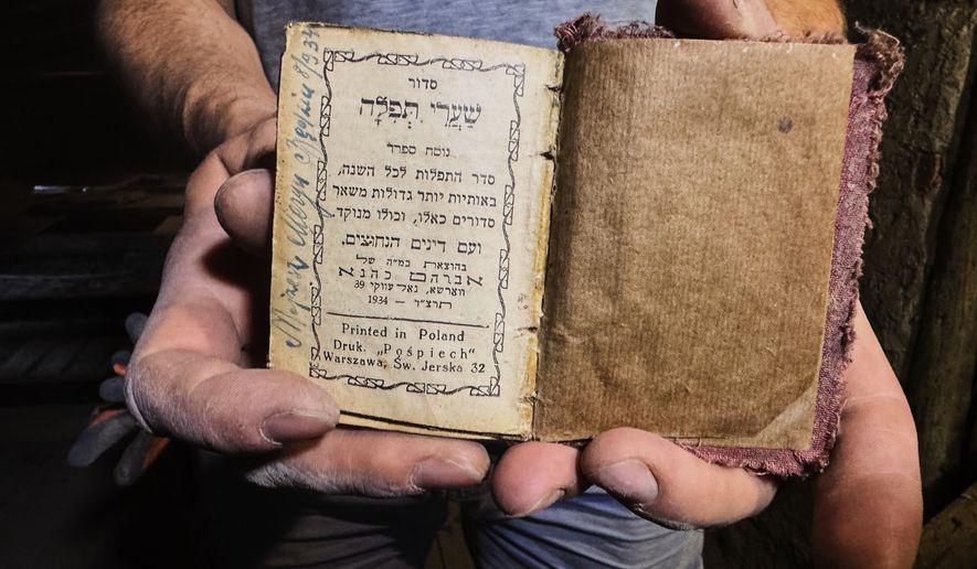 Wojciech Mazan, museologist and art historian shows a Hebrew prayer book from 1934, found in the attic of the "Bedzin Ghetto Fighters Memorial" house in Bedzin, Poland, on May 29, 2026. (AP Photo/Rafal Niedzielski)