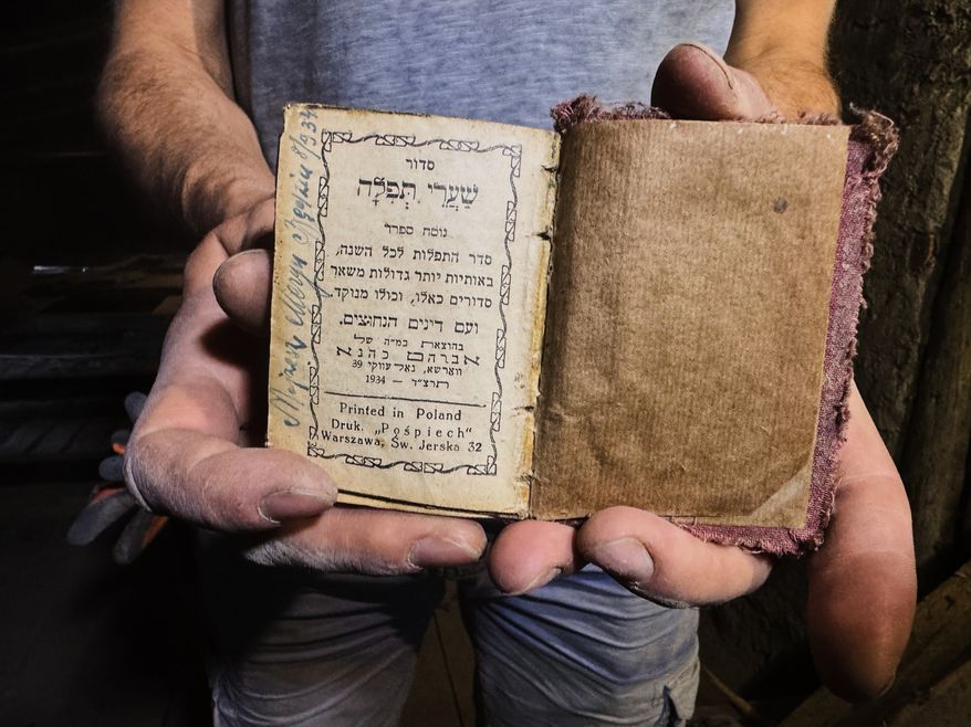 Wojciech Mazan, museologist and art historian shows a Hebrew prayer book from 1934, found in the attic of the "Bedzin Ghetto Fighters Memorial" house in Bedzin, Poland, on May 29, 2026. (AP Photo/Rafal Niedzielski)