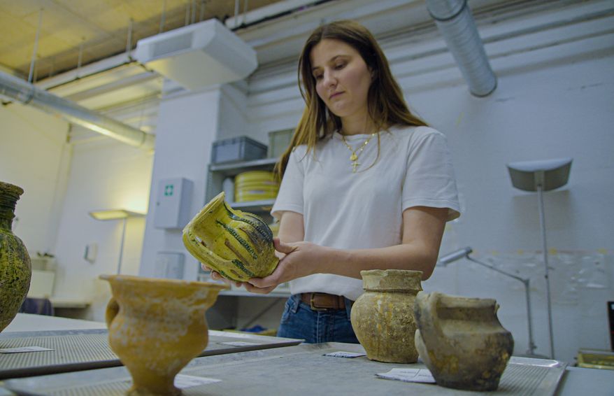 Archaeologist Valentine Breloux, holds ceramic fragments discovered during excavations outside Notre-Dame Cathedral in Paris, Monday, June 1, 2026. (AP Photo/Nicolas Garriga)