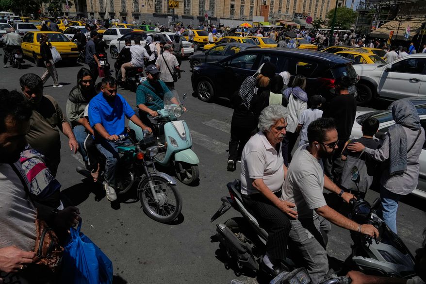 Pedestrians and vehicles cross an intersection around Tehran's historic Grand Bazaar, Iran, Monday, June 1, 2026. (AP Photo/Vahid Salemi)
