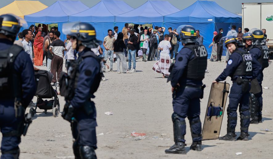 Police conduct a search operation at a makeshift camp of migrants who want to cross the English Channel to Britain near Dunkirk, northern France, Wednesday, May 27, 2026. (AP Photo/Jean-Francois Badias)