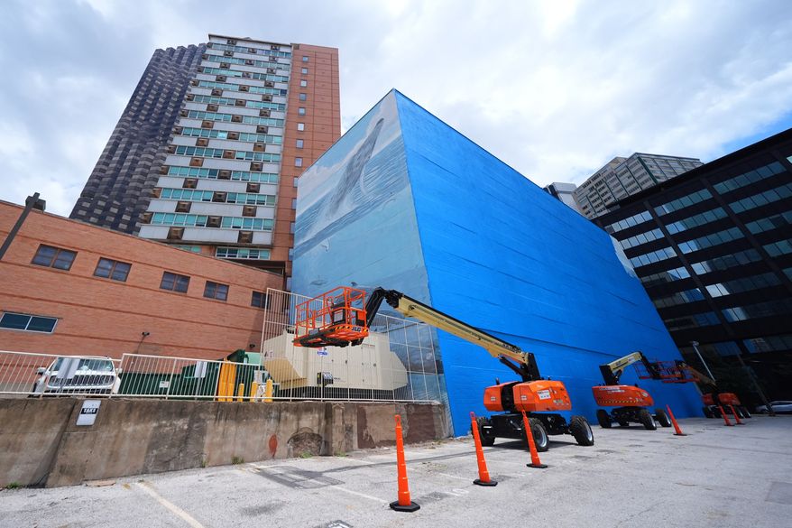 A section of a mural, known as the "Whaling Wall 82," created by artist Wyland, is visible as part of it on the right side of the building was painted over, Monday, May 18, 2026, in Dallas. (AP Photo/Julio Cortez)