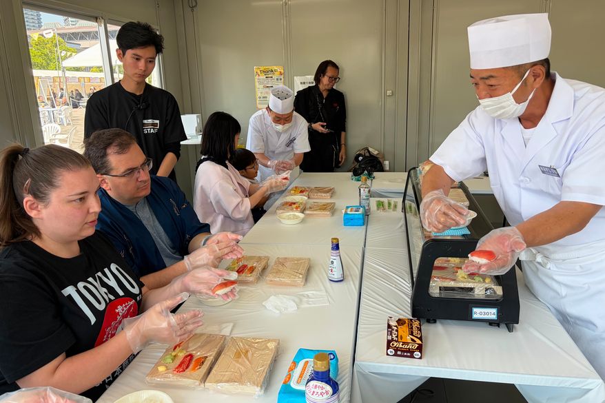 Brittany Nevins and her husband Kevin, both from Erlander, Ky., try making sushi for the first time with a sushi master in Tokyo, on May 15, 2026. (AP Photo/Yuri Kageyama)