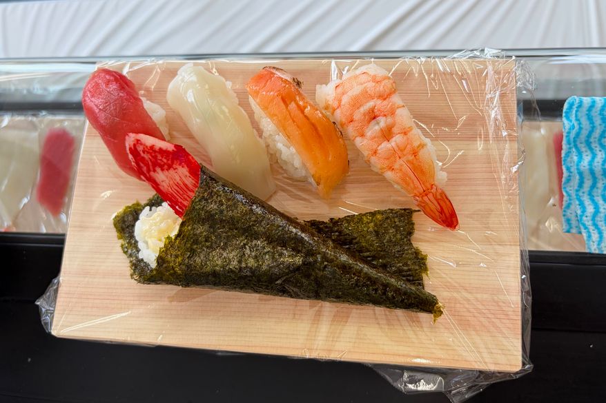 The pieces of sushi that just got made by Tsuneo Suzuki, a master sushi chef, are lined up on a plate at a class for beginners in Tokyo, on May 15, 2026. (AP Photo/Yuri Kageyama)