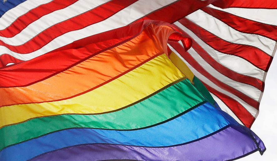 An LGBTQ+ pride flag flies beneath a U.S. flag at the Stonewall National Monument in New York on Oct. 11, 2017. (AP Photo/Mark Lennihan) **FILE**