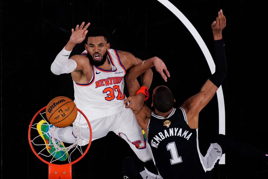 New York Knicks center Karl-Anthony Towns (32) shoots past San Antonio Spurs forward Victor Wembanyama (1) during the first half of Game 1 of the NBA Finals basketball series, Wednesday, June 3, 2026, in San Antonio. (AP Photo/Eric Gay)