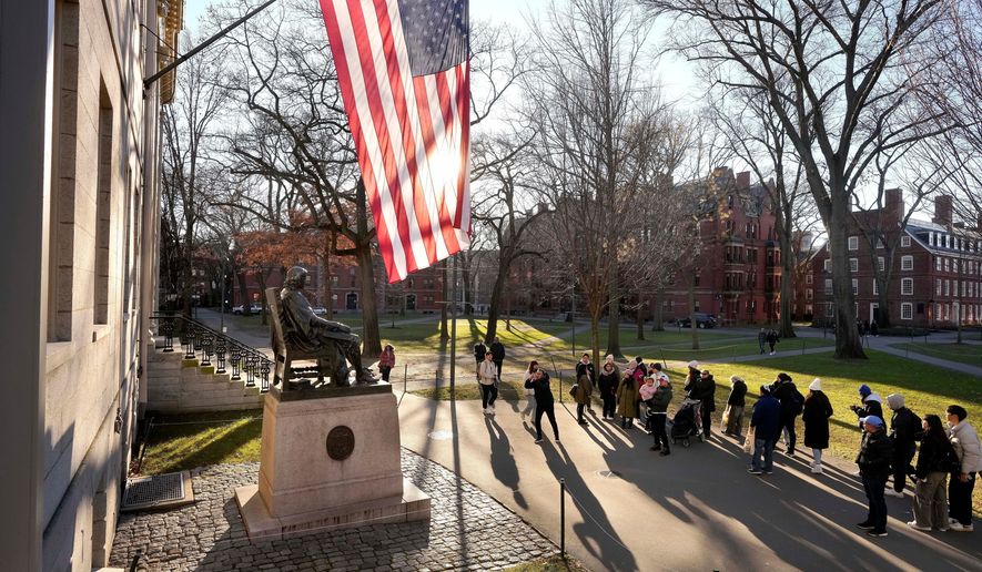 People take photos near a John Harvard statue, left, on the Harvard University campus, Jan. 2, 2024, in Cambridge, Mass. (AP Photo/Steven Senne, File)