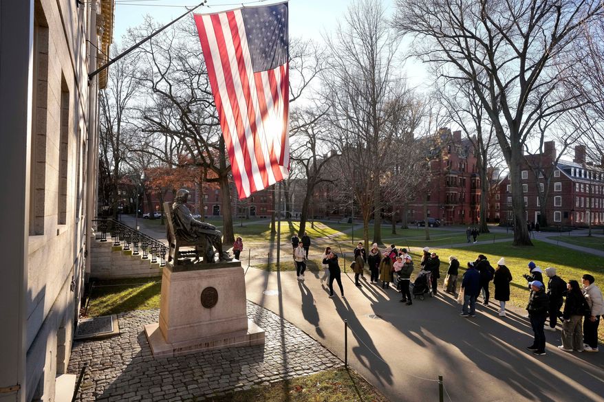 People take photos near a John Harvard statue, left, on the Harvard University campus, Jan. 2, 2024, in Cambridge, Mass. (AP Photo/Steven Senne, File)