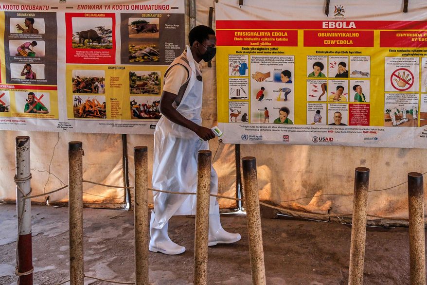 A health worker walks past Ebola warning and instruction posters at a temporary health clinic at the Mpondwe border crossing linking Uganda and the Democratic Republic of the Congo, Thursday, June 4, 2026. (AP Photo/Hajarah Nalwadda)