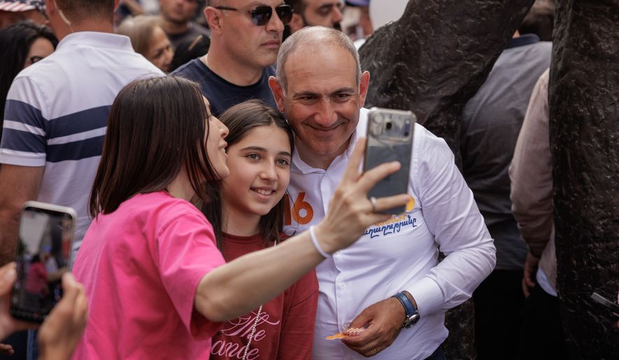 Armenian Prime Minister Nikol Pashinyan poses for a selfie photo with a supporter as he walks on Northern Avenue in Yerevan, Armenia, Monday, June 1, 2026, during public celebrations marking International Children's Day. (AP Photo/Anthony Pizzoferrato)