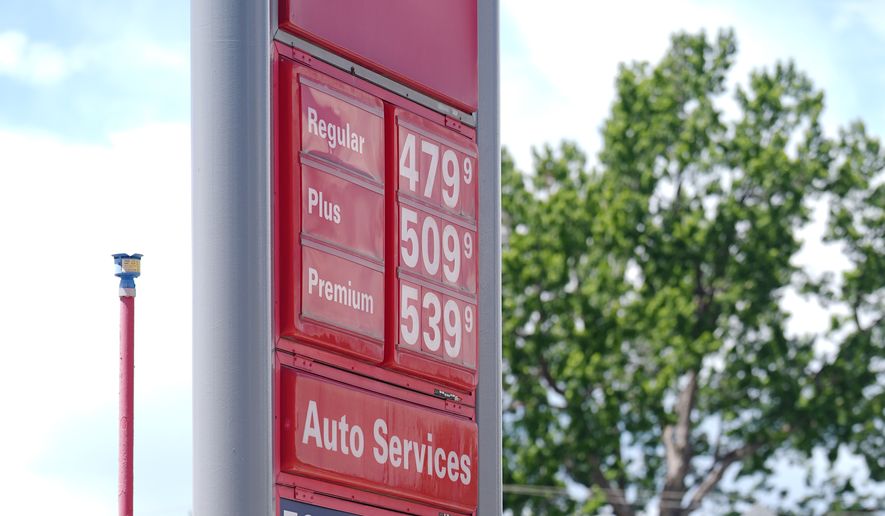 As the daytime high temperature soars into the 80s, a United States Postal Service postman keeps cool by standing in the shade of a gasoline station sign posting the per-gallon prices for the various grades of fuel available Thursday, June 4, 2026, in central Denver. (AP Photo/David Zalubowski)