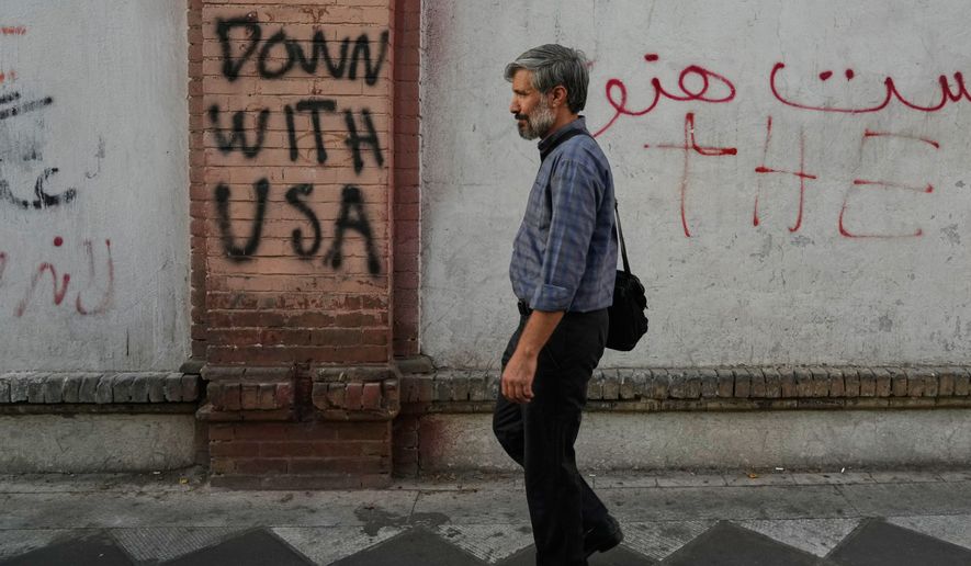 A man walks past anti-U.S. graffiti painted on the wall of the British Embassy in Tehran, Iran, Saturday, June 6, 2026. (AP Photo/Vahid Salemi)